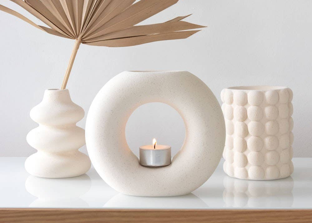 Cream Speckle Bubble Tealight Wax Warmer surrounded by decorative vases and foliage on a minimalist display.