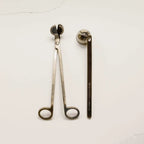 Brass candle wick trimmer and candle snuffer on a white background.