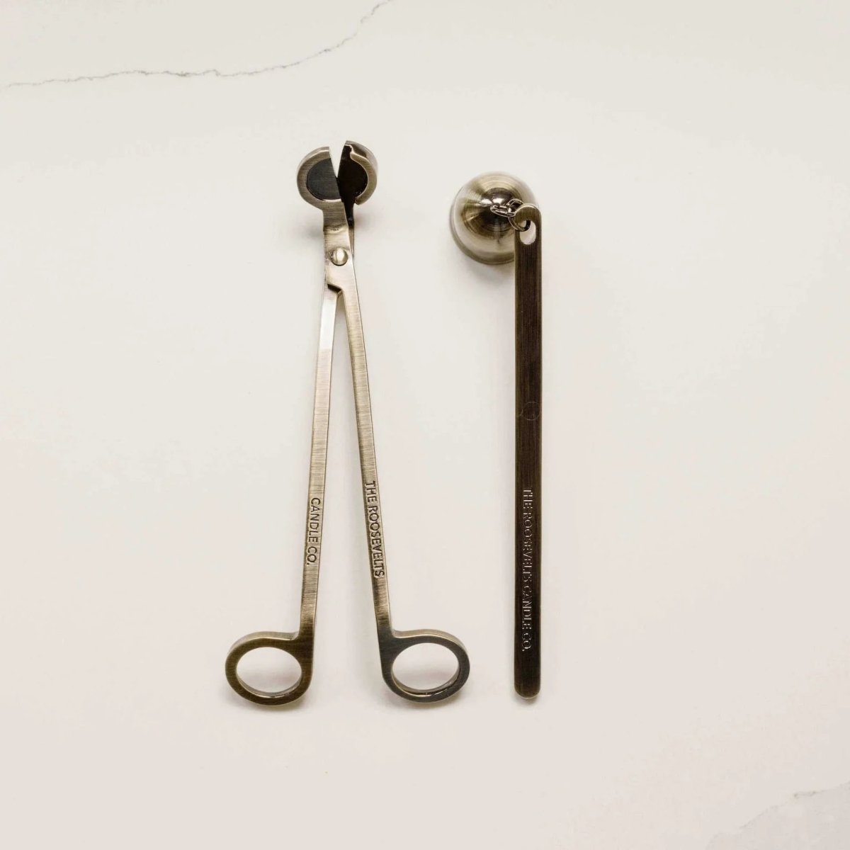 Brass candle wick trimmer and candle snuffer on a white background.