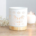 Matte ceramic butterfly oil burner with cut-out design illuminating a tealight candle.