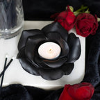 Black rose tealight candle holder with a lit tealight, surrounded by red roses and black decor.