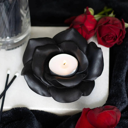 Black rose tealight candle holder with a lit tealight, surrounded by red roses and black decor.