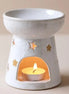 Starry wax melt ceramic warmer with star cut-outs, featuring a tealight candle in the base, creating a warm ambiance.