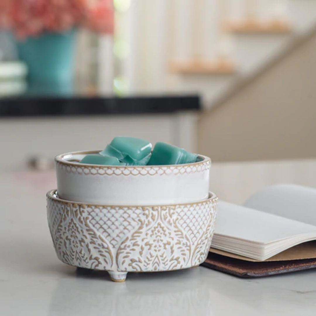 Vintage glam wax melt warmer with elegant design holding teal wax melts on a marble surface beside a notebook.