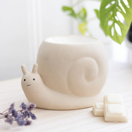Beige stone snail-shaped wax warmer with carved spiral shell and smiling face, shallow bowl top.