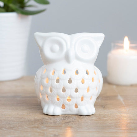White glossy ceramic owl wax warmer with teardrop cutouts glowing from a lit tealight.
