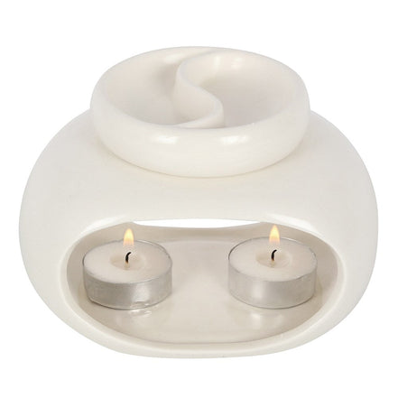 White glossy ceramic double oil burner/wax warmer with a divided round top dish and two lit tealights in metal cups inside an arched front cavity
